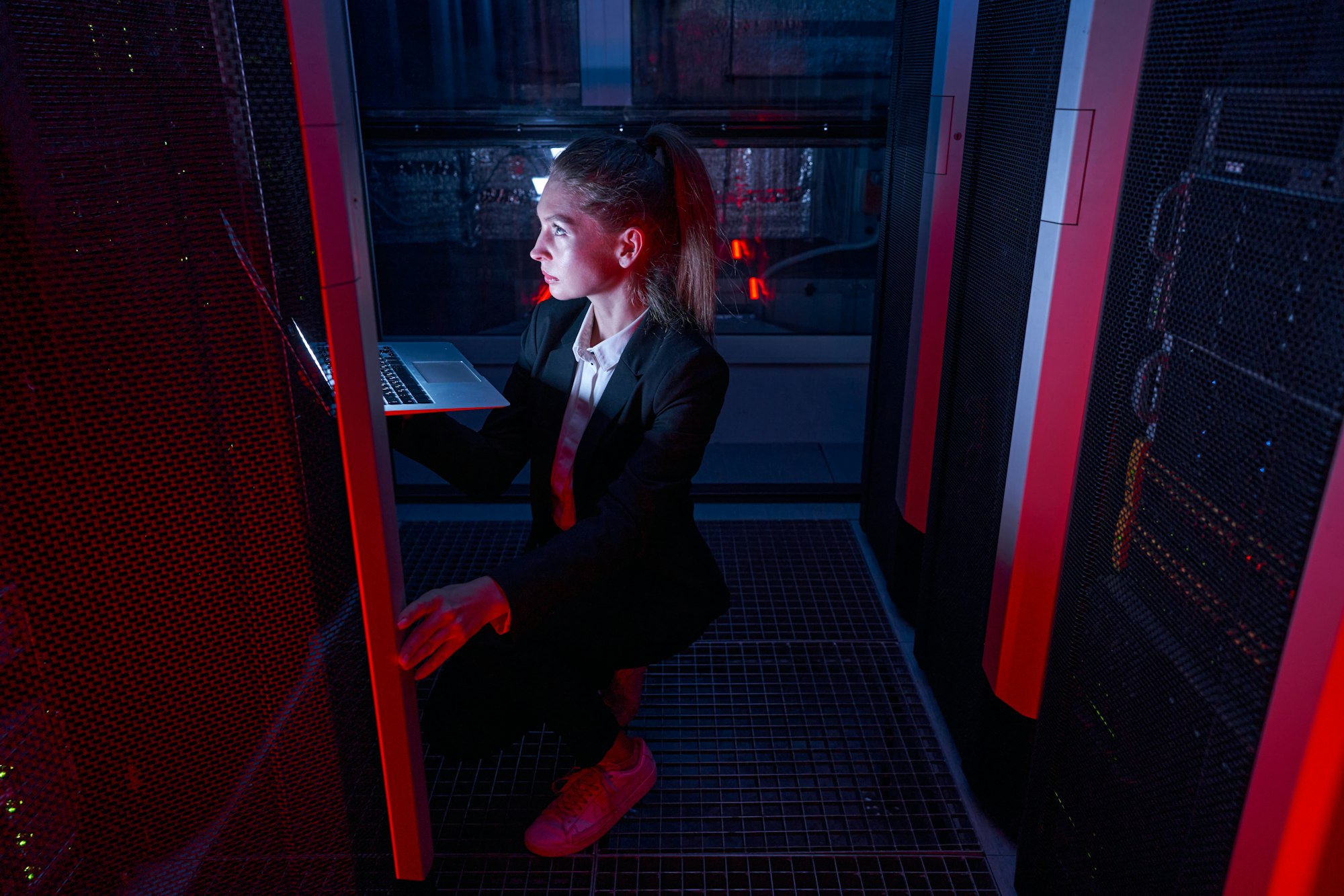System administrator with laptop examining in server room
