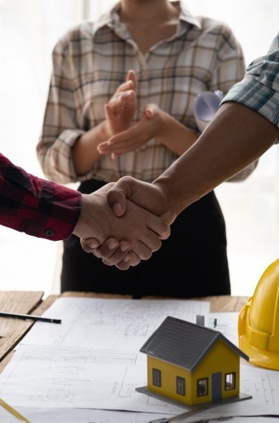 Architect and engineer construction workers shaking hands while working for teamwork.